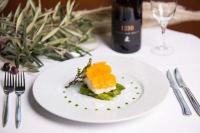 Traiteur Monsieur Louis Traiteur Marsillargues #4 Assiette gastronomique avec asperges, poisson et tranches de légumes jaunes, accompagnée d'une bouteille de vin rouge.