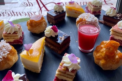 Traiteur Traiteur Lallemand Montblanc #5 Assortiment de pâtisseries miniatures sur un plateau noir, avec une verrine de coulis rouge au centre.