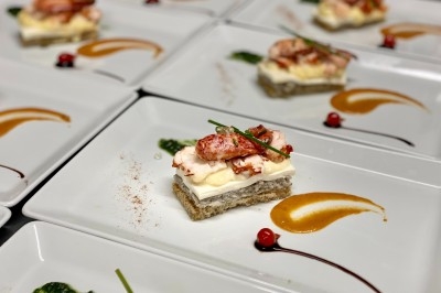 Traiteur Traiteur Lallemand Montblanc #1 Assiette gastronomique avec une entrée composée de morceaux de homard, mousse, pain, et décorations de sauces colorées.