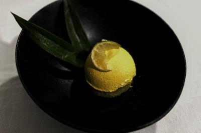 Traiteur Jacques Lafargue Traiteur Chaponost #3 Dessert jaune en forme de dôme, garni d'une tranche de citron et accompagné de feuilles vertes, présenté dans une assiette…