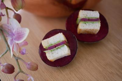 Traiteur Arômes et Sens Neuilly-sur-Seine #3 Deux mini-sandwichs garnis de légumes verts et d'oignons rouges, posés sur des tranches de betterave, avec une orchidée en…