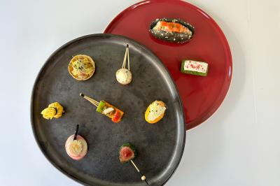 Traiteur Arômes et Sens Neuilly-sur-Seine #2 Assortiment de bouchées apéritives variées présentées sur des assiettes noire et rouge.