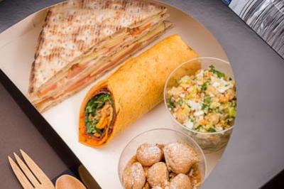 Plateau-repas comprenant un sandwich, un wrap, deux salades, des desserts et une bouteille d'eau.