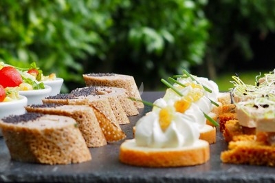 Assortiment de canapés variés disposés sur une ardoise, avec un fond de verdure flou.