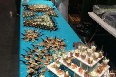 Buffet avec présentation soignée de plats variés, incluant fruits de mer, verrines et amuse-bouches, sur une nappe turquoise.