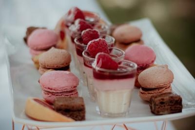 Traiteur Stéphane Portier Traiteur Le Plessis-Macé #4 Plateau de desserts comprenant des macarons roses, verrines garnies de framboises et morceaux de gâteau au chocolat.