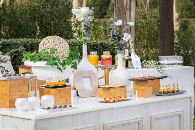 Traiteur Gaudefroy Receptions Ollioules #1 Table de buffet en extérieur avec décorations florales, verrerie, boissons et assortiments de bouchées apéritives.