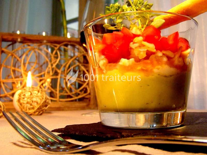 Verrine composée de purée d'avocat, tomates en dés, fromage râpé et décorée d'un gressin et d'herbes fraîches.