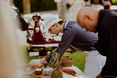 Traiteur Au Bois du Bon Sejour Aubeterre #5 Un cuisinier prépare des plats avec du saumon et des ingrédients frais lors d'un événement en extérieur.