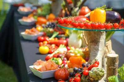 Traiteur Le Moulin des Quatre Saisons La Flèche #4 Table garnie de légumes et fruits colorés disposés sur des présentoirs en extérieur.