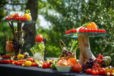 Traiteur Le Moulin des Quatre Saisons La Flèche #2 Table décorée en extérieur avec des fruits et légumes frais disposés sur des supports en bois et en paniers.