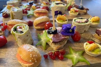 Traiteur Valérie Pons Traiteur Montauban #1 Plateau de bouchées variées comprenant wraps, mini-sandwichs, fruits et garnitures colorées sur une planche en bois.