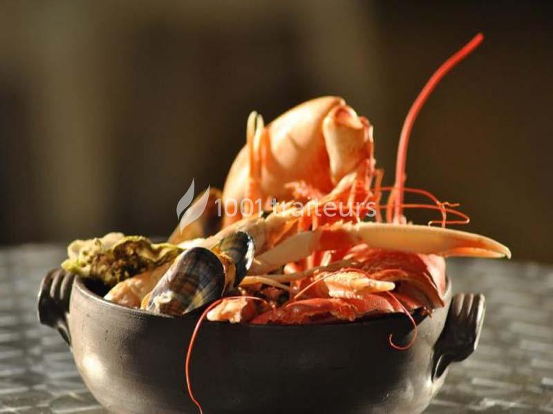 Assortiment de fruits de mer dans un plat en céramique, comprenant crevettes, coquillages et crustacés.