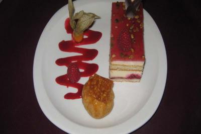 Dessert composé d'un entremets aux fruits rouges, d'une pâte à choux caramélisée et d'un coulis décoratif.