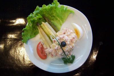 Assiette contenant des asperges, de la salade, une tomate, un œuf dur, une préparation crémeuse et une olive noire.