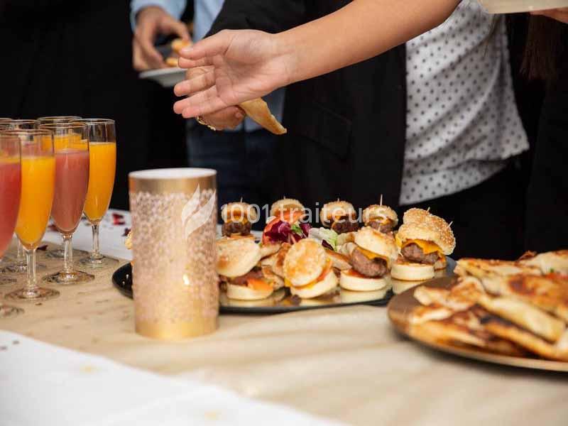 Traiteur Le Maydane Avs Clamart #1 Plateau de mini-burgers et verres de cocktails sur une table lors d'un buffet, avec une main se servant.