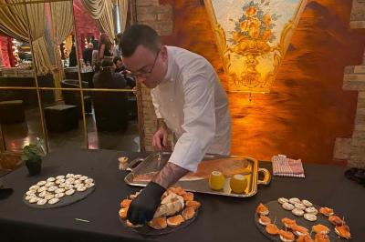 Traiteur Him Traiteur Sartrouville #4 Un chef prépare des plats raffinés sur une table décorée, avec des assiettes de bouchées et un fond élégant.