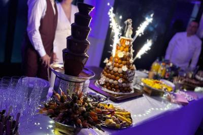 Traiteur Him Traiteur Sartrouville #2 Buffet de desserts avec fontaine de chocolat, pièce montée éclairée de cierges et fruits frais sur une table décorée.