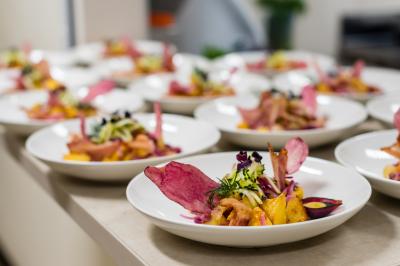 Assiettes de plats colorés avec légumes, chips de betterave et herbes fraîches alignées sur un plan de travail.