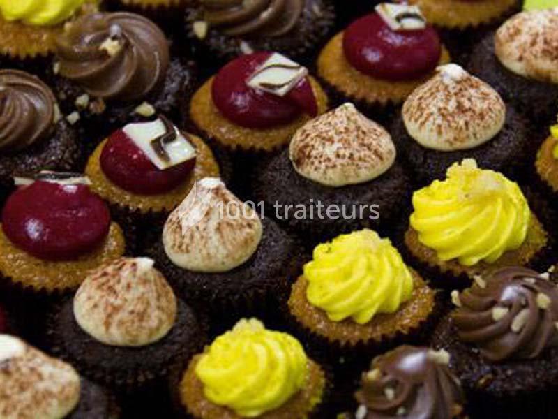 Traiteur Le Regent Traiteur Saint-Germain-Laval #1 Assortiment de petits cupcakes décorés de glaçages colorés et variés disposés en rangées serrées.