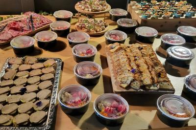 Buffet avec charcuterie, terrines, pains garnis et verrines colorées disposés sur une table en bois.