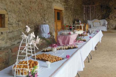 Traiteur Marc et Sophie Traiteur Cuisine & Services Limas #2 Table de buffet décorée avec des fleurs roses, disposée dans une salle en pierre avec des desserts et des amuse-bouches.