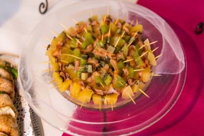Brochettes de fruits variés, notamment kiwi et ananas, disposées en cercle sur une assiette transparente.