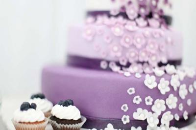 Traiteur Rubis Receptions Magny-le-Hongre #5 Gâteau à étages violet décoré de fleurs en sucre blanches, accompagné de cupcakes garnis de crème et de myrtilles.