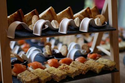 Plateau de service à deux niveaux avec des amuse-bouches variés, incluant saumon fumé, quiches et petits pains.