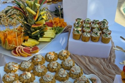 Plateau de buffet avec fruits frais, verrines garnies et petits amuse-bouches disposés sur une table blanche.
