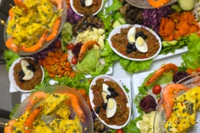 Plats variés composés de salades, crevettes, œufs, olives et légumes, présentés sur une table garnie de verdure.