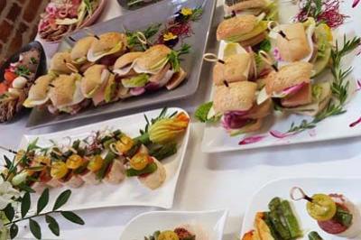 Buffet de plats variés comprenant amuse-bouches, brochettes et légumes, disposés sur une table blanche.