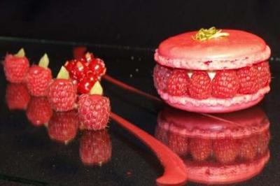 Traiteur Frederic Fouquet Créateur d'Emotions Culinaires Faverges #2 Macaron rose garni de framboises fraîches, accompagné de framboises et groseilles disposées sur une surface noire.