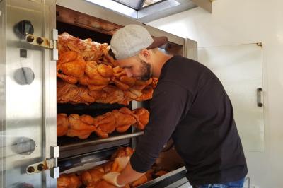 Traiteur La Cocotte Mobile Champigny-sur-Marne #2 Un homme vérifie des poulets rôtis disposés sur des broches dans un four professionnel.