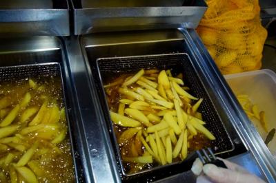 Traiteur La Cocotte Mobile Champigny-sur-Marne #3 Frites en cours de cuisson dans une friteuse industrielle, avec des pommes de terre fraîches visibles à proximité.