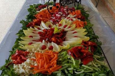 Plateau de crudités colorées avec carottes, concombres, endives, radis et poivrons, disposé sur une table.