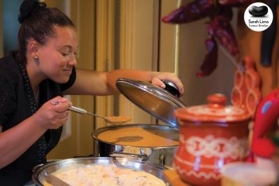 Une femme sert une soupe chaude dans une cuisine avec des plats et des décorations traditionnelles.