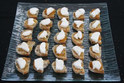 Tranches de pain garnies de fromage blanc et de confiture, disposées en rangées sur un plateau en verre.