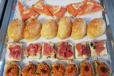 Plateau de canapés variés avec saumon, jambon cru, tapenade et petits pains au sésame sur nappe blanche.
