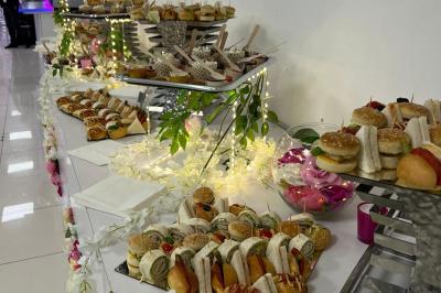 Traiteur L'instant Gourmand Beauchamp #2 Buffet de mini-sandwichs variés et desserts disposés sur une table décorée de fleurs et de lumières.
