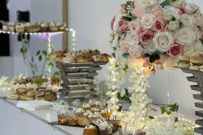 Traiteur L'instant Gourmand Beauchamp #4 Buffet décoré avec des fleurs blanches et roses, présentant des pâtisseries et amuse-bouches sur des présentoirs élégants.