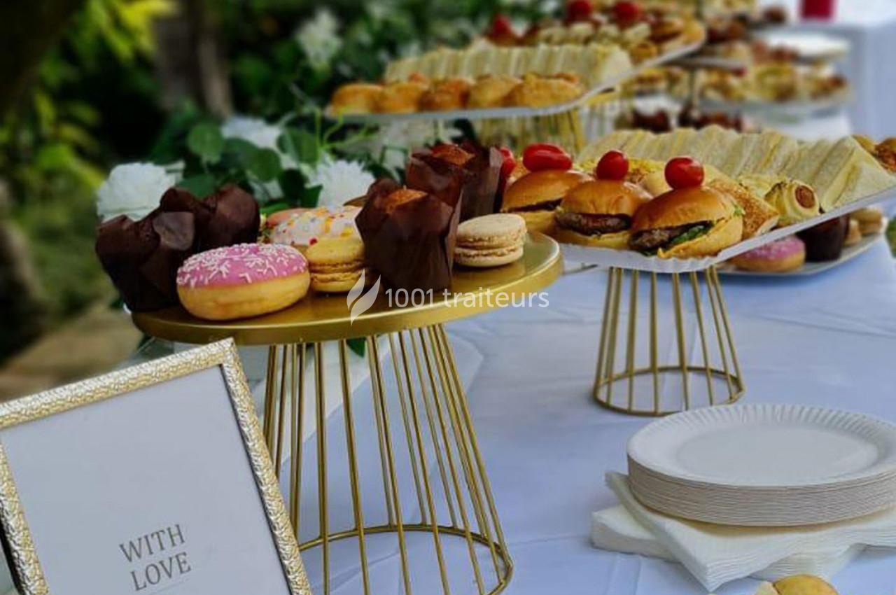 Traiteur L'instant Gourmand Beauchamp #1 Buffet avec pâtisseries, sandwichs et desserts variés disposés sur des plateaux dorés sur une table blanche.