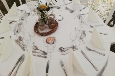 Traiteur Lou Pignatoun Grasse #4 Table ronde dressée avec nappes blanches, couverts, serviettes pliées, verres et centre de table floral.