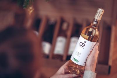 Traiteur Les Vins Oé Lyon 9 #3 Une personne tient une bouteille de vin blanc biologique devant une caisse contenant d'autres bouteilles.