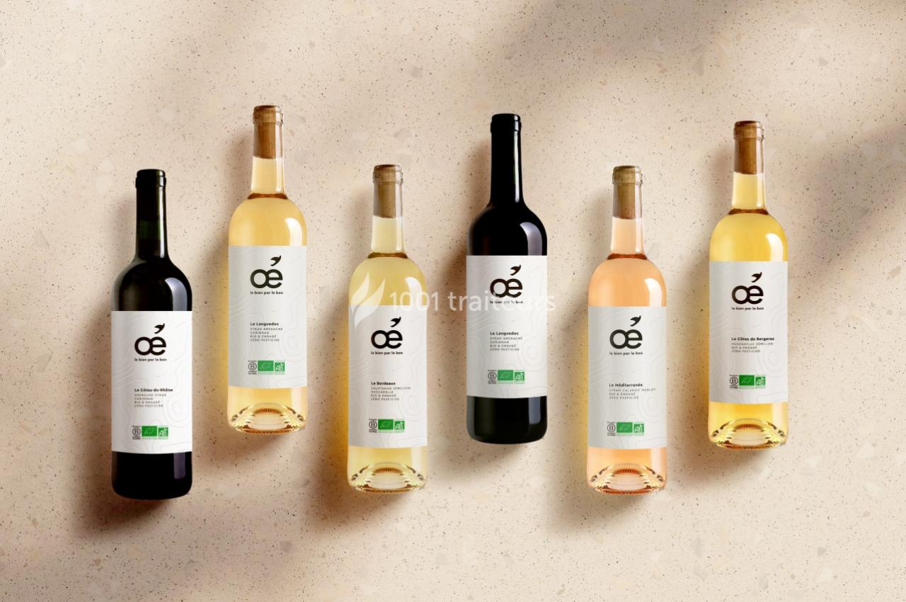 Traiteur Les Vins Oé Lyon 9 #1 Six bouteilles de vin bio aux étiquettes blanches alignées sur une surface beige avec une lumière douce.