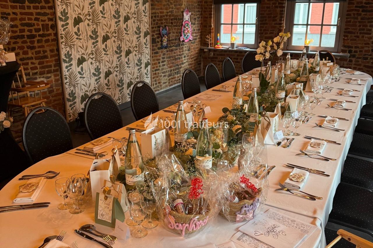 SALON MONET : PETIT COMITE (40 PERSONNES) Table dressée pour un repas festif dans une salle en briques, décorée de lumières suspendues et de détails élégants.