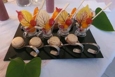 Traiteur Karine Roger Traiteur Fessanvilliers-Mattanvilliers #3 Plateau de verrines décorées de feuilles colorées, accompagné de macarons, présenté sur une table blanche.