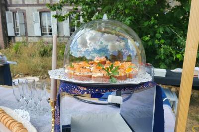 Traiteur Karine Roger Traiteur Fessanvilliers-Mattanvilliers #2 Plateau de bouchées apéritives sous une cloche en verre, présenté sur une table en extérieur près d'un bâtiment ancien.