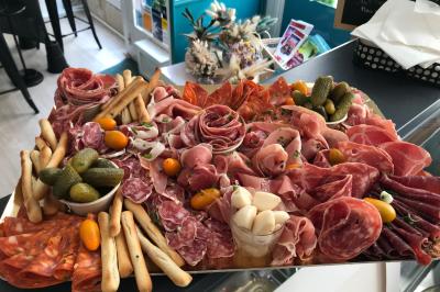 Traiteur L’Atelier AÔI, Traiteur Franco-Japonais Senlis #4 Plateau de charcuterie variée avec cornichons, gressins, tomates cerises et ail mariné, présenté sur un comptoir.