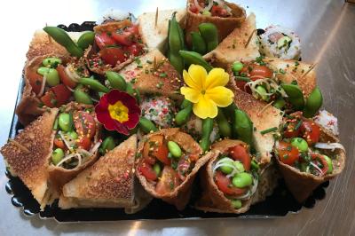 Traiteur L’Atelier AÔI, Traiteur Franco-Japonais Senlis #3 Plateau de bouchées variées comprenant des rouleaux garnis de légumes, des tranches de pain grillé et des fleurs comestibles.